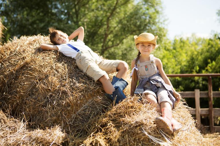 Zwei kleine Kinder, ein Bruder und eine Schwester, ruhen sich im Sommer auf dem Heuboden eines Bauernhofs aus.