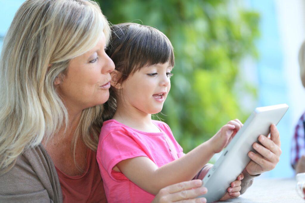 Eine Frau und ein Kind nutzen gemeinsam ein Tablet, um das Buchungssystem für die Ferienhaus Verwaltung zu überprüfen