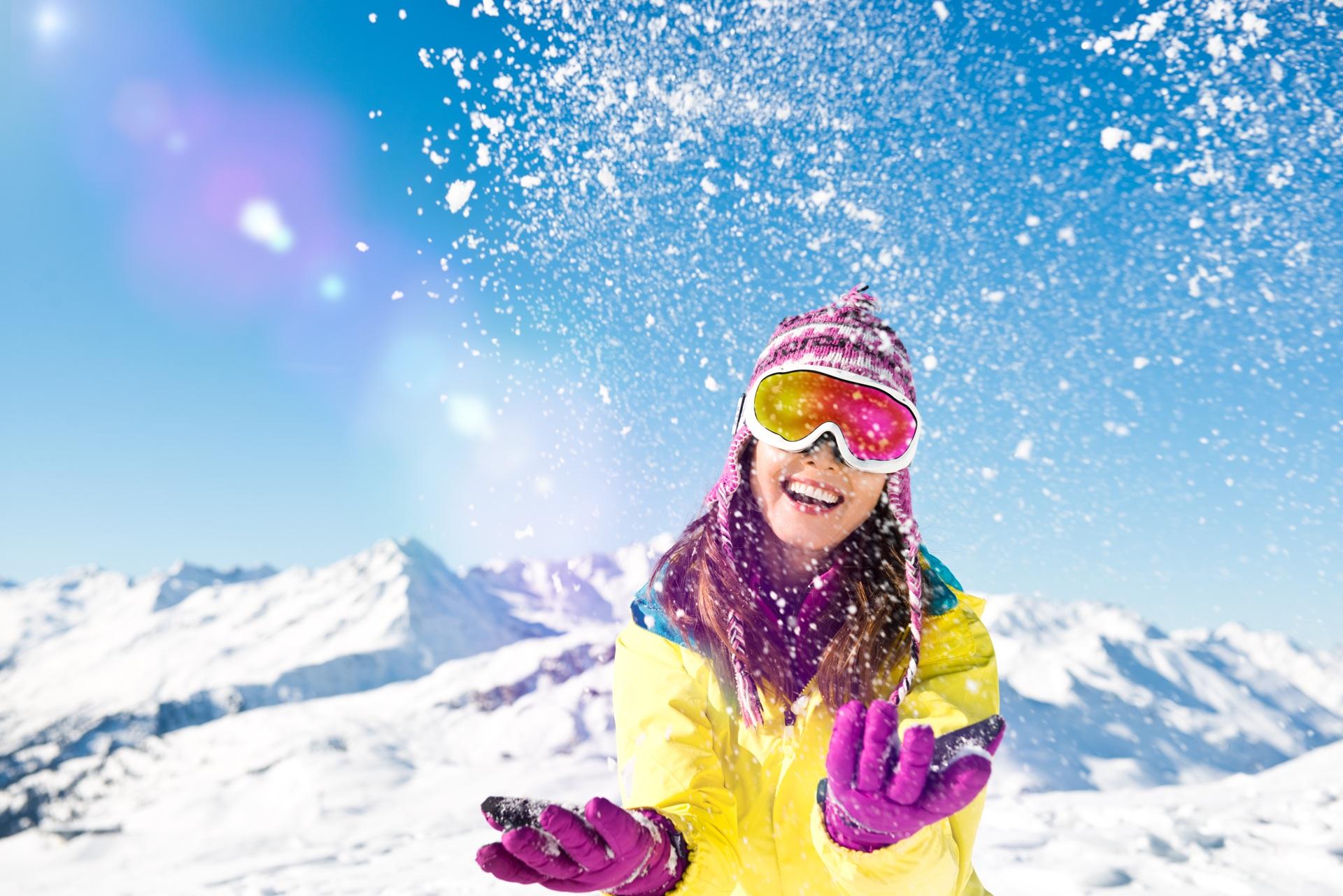 Junge Frau wirft Schnee vor Alpenkulisse | Schlittschuhe